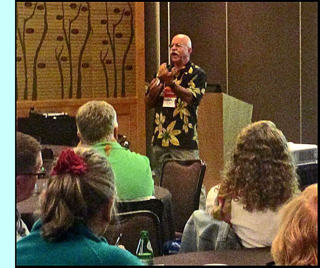 Craig Phillips is standing in front of the lecturn and speaking into a microphone during his lecture.