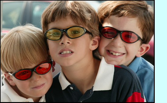 photo shows 3 young children posing together wearing sunglasses tinted in different colors.