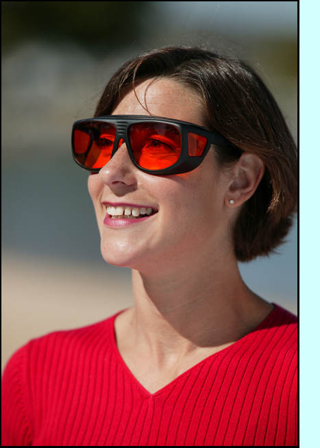photo shows a woman smiling and red-tinted sunglasses with top and side shields.